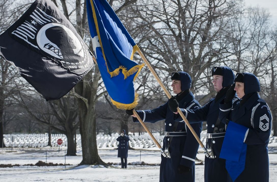 Airmen holding the POW flag in veterans cemetery
