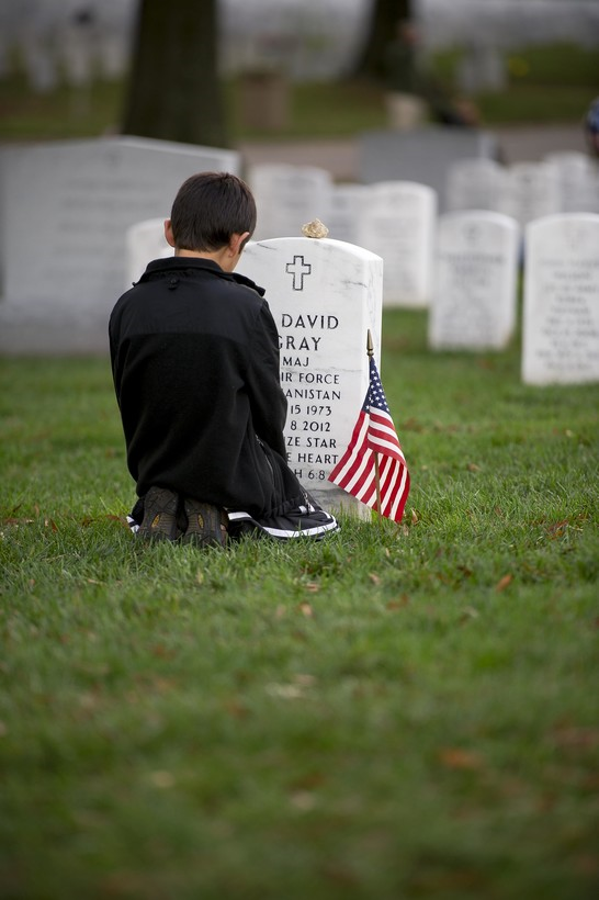 child kneeling by a headstone
