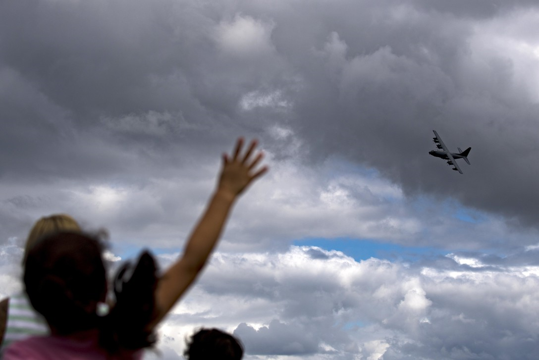 people waving at an aircraft flying overhead