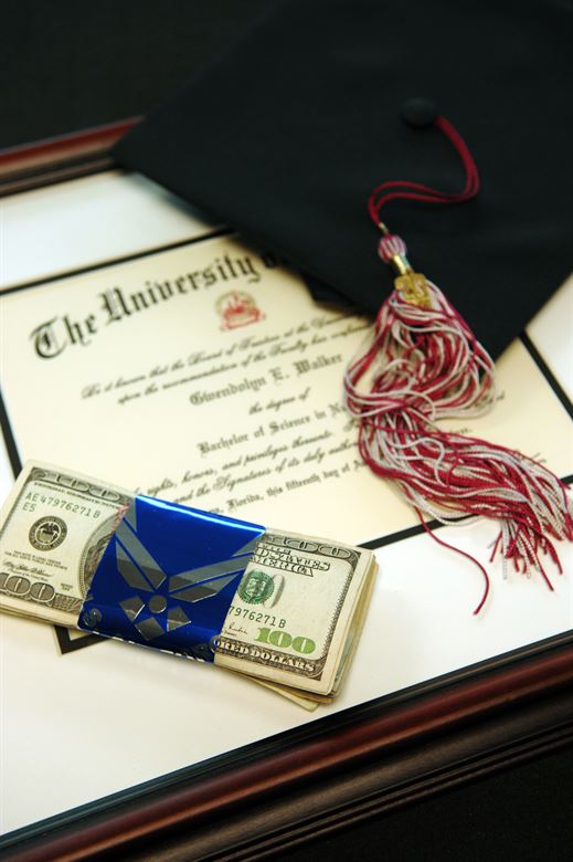 diploma with a cap and stack of mony on top of it