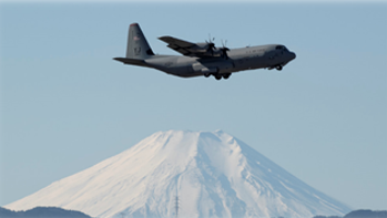 C130 flying with a snow covered montain in the background