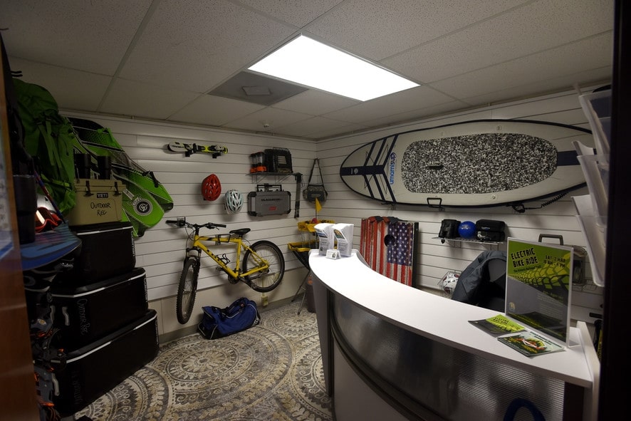 Ourdoor Rec store, bicycle, paddle board, helmets, and coolers hanging on the wall 