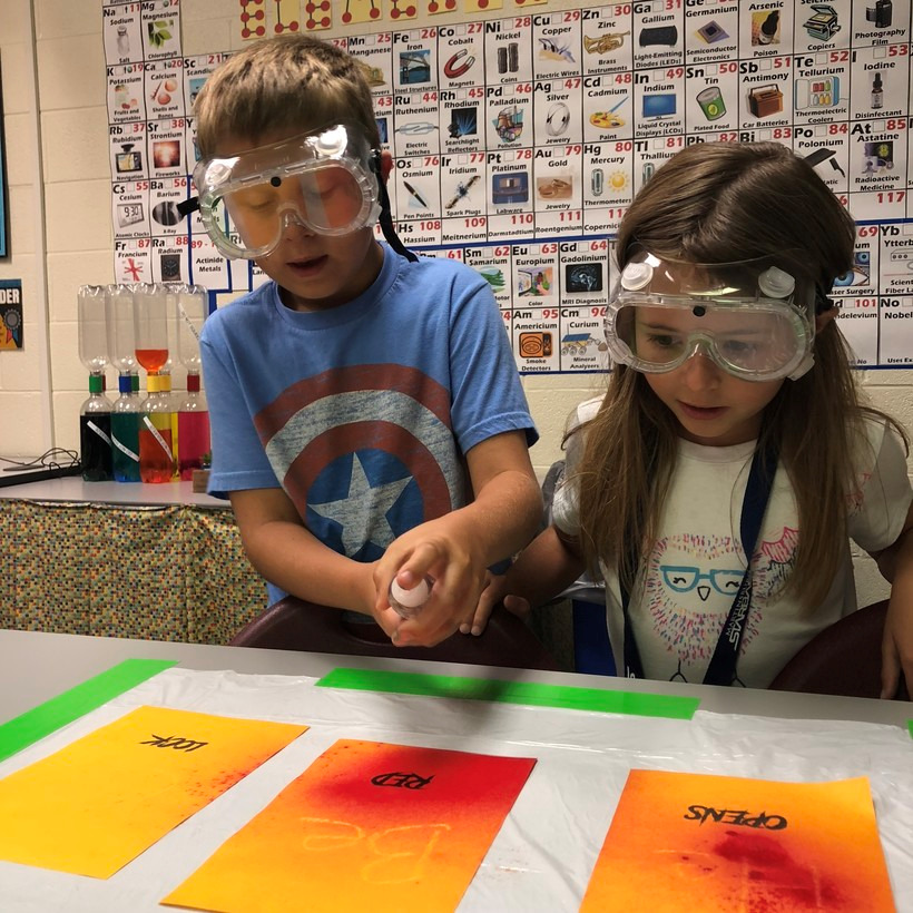 2 children wearing goggles painting